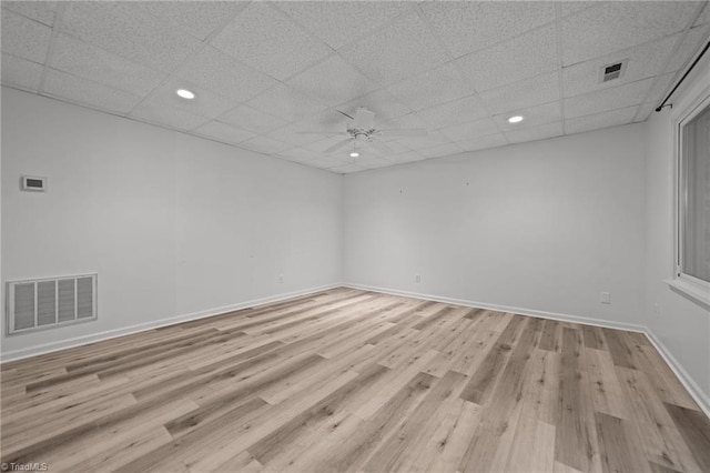 unfurnished room with ceiling fan, light wood-type flooring, and a drop ceiling