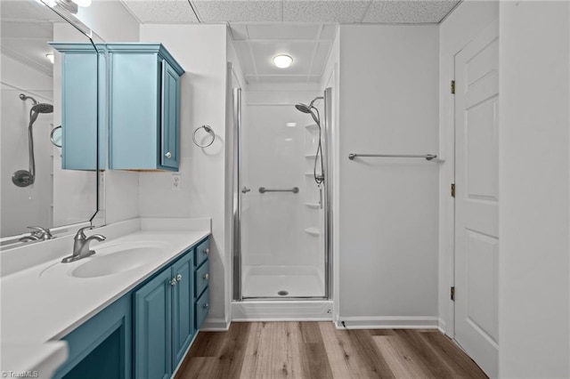 bathroom featuring vanity, a drop ceiling, hardwood / wood-style floors, and a shower with door