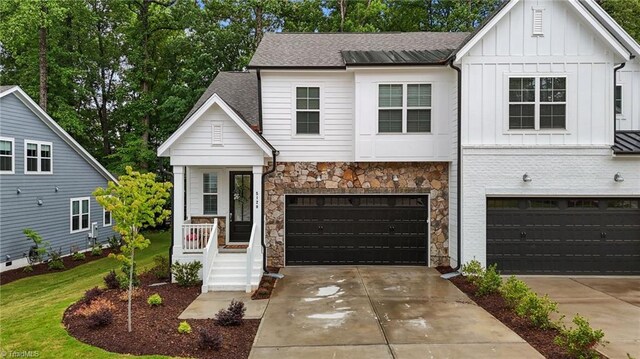 5120 Whaitley Ln, Greensboro, NC 27407 - view of front facade with board and batten siding, concrete driveway, an attached garage, stone siding, and a shingled roof