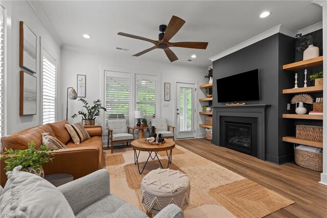 5120 Whaitley Ln, Greensboro, NC 27407 - living room featuring plenty of natural light, wood finished floors, a ceiling fan, a glass covered fireplace, and ornamental molding
