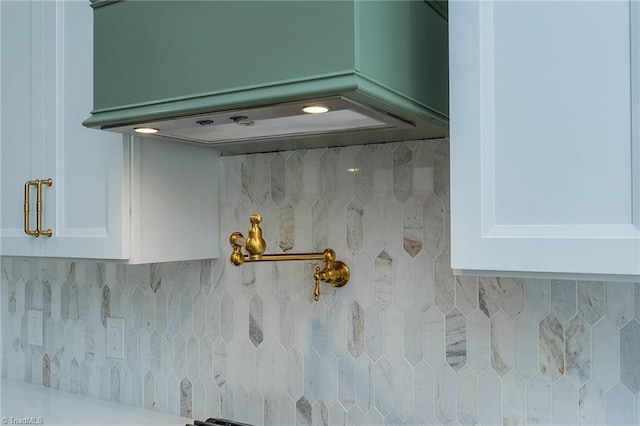 details featuring premium range hood, white cabinetry, and tasteful backsplash