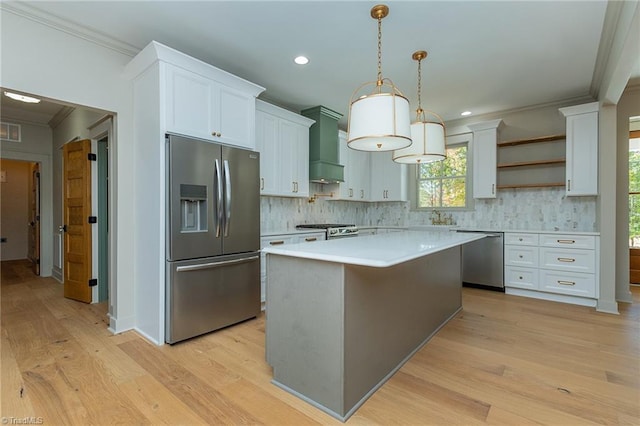 kitchen featuring stainless steel appliances, a center island, pendant lighting, light wood-type flooring, and white cabinetry