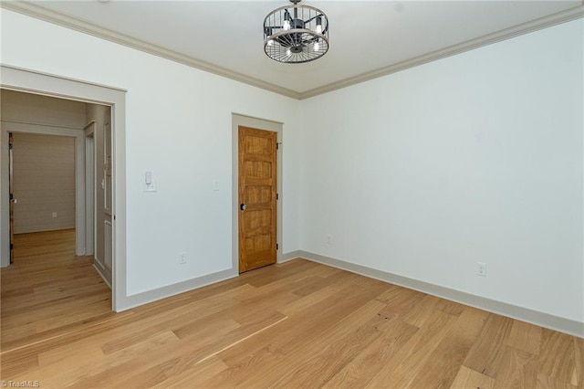 empty room featuring crown molding, a notable chandelier, and light hardwood / wood-style flooring