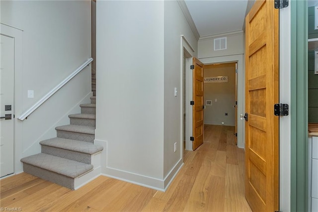 stairs featuring crown molding and hardwood / wood-style flooring