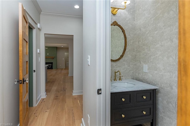 bathroom with vanity, crown molding, wood-type flooring, and a fireplace