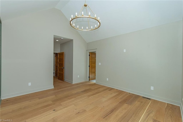 empty room with vaulted ceiling, light hardwood / wood-style flooring, and a notable chandelier