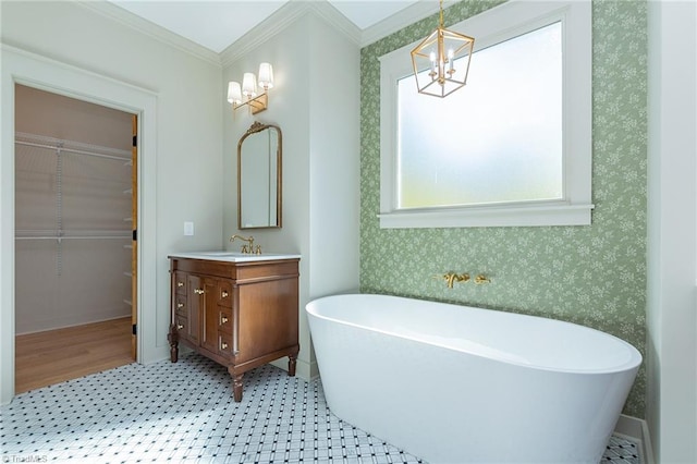 bathroom featuring vanity, crown molding, an inviting chandelier, and a bathtub