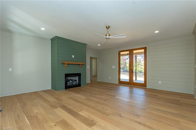 unfurnished living room with light hardwood / wood-style floors, french doors, a fireplace, and crown molding