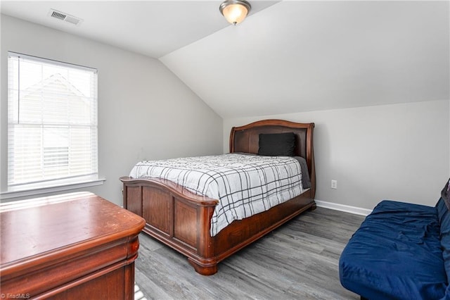 bedroom with multiple windows, hardwood / wood-style floors, and vaulted ceiling