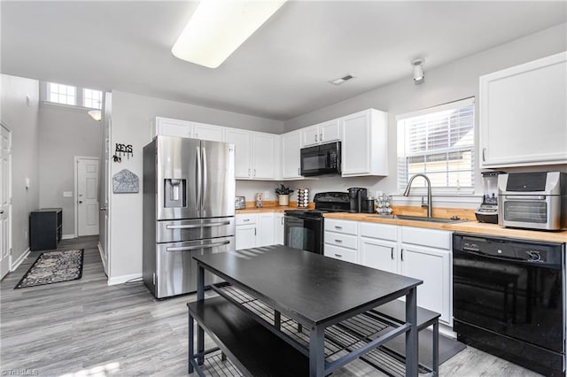 kitchen featuring white cabinetry, sink, and black appliances