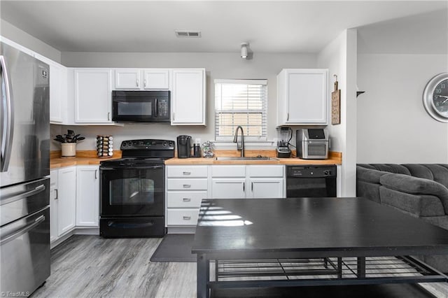 kitchen featuring white cabinets, sink, light hardwood / wood-style floors, and black appliances