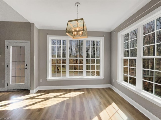 unfurnished dining area with plenty of natural light, baseboards, and wood finished floors