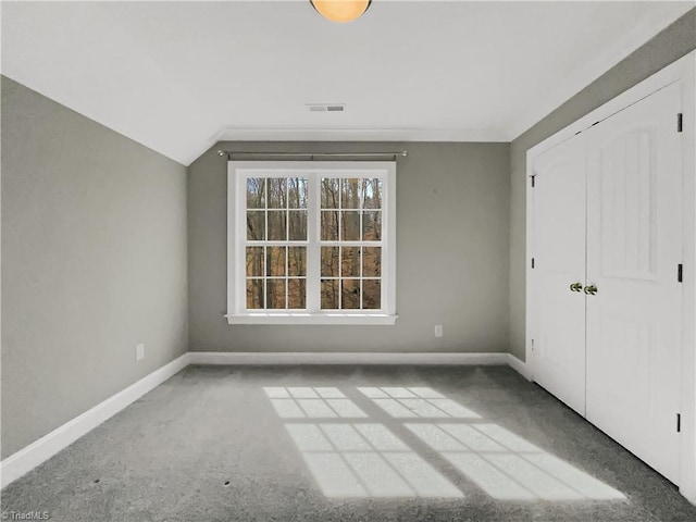 unfurnished bedroom featuring visible vents, baseboards, a closet, and vaulted ceiling