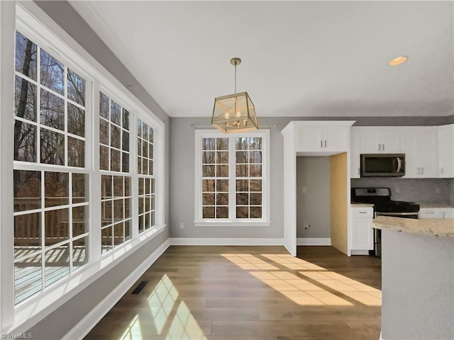 kitchen featuring appliances with stainless steel finishes, white cabinets, baseboards, dark wood-style flooring, and light stone countertops