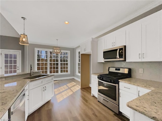 kitchen featuring light stone countertops, stainless steel appliances, wood finished floors, white cabinetry, and a sink