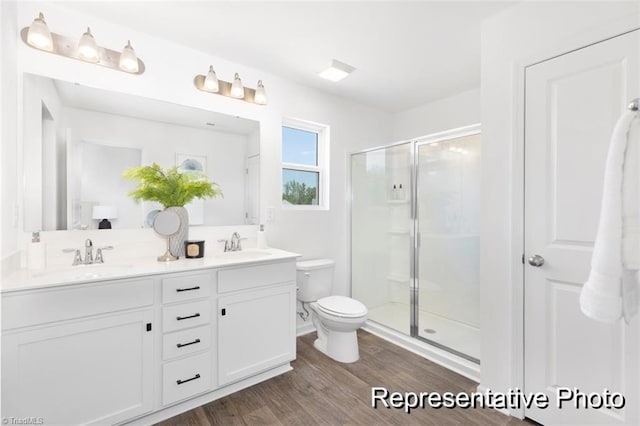 bathroom featuring vanity, hardwood / wood-style flooring, a shower with door, and toilet