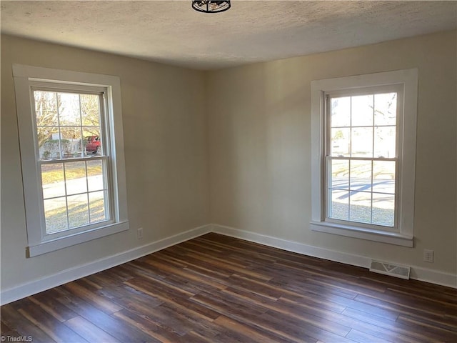 empty room featuring dark wood-type flooring and a textured ceiling