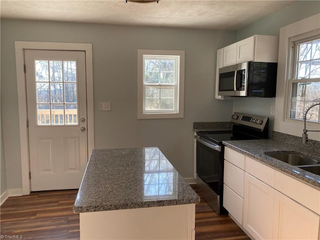 kitchen with sink, white cabinetry, a center island, dark stone countertops, and appliances with stainless steel finishes