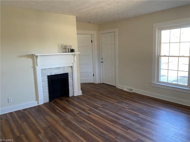 unfurnished living room with a healthy amount of sunlight, a textured ceiling, and dark hardwood / wood-style flooring