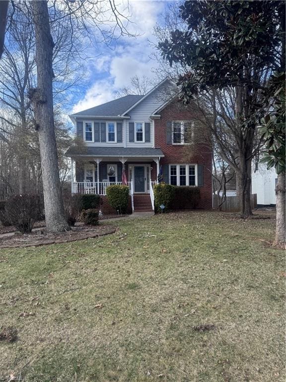 view of front facade featuring a front lawn, covered porch, and brick siding