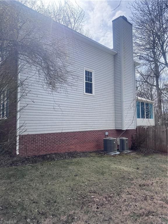 view of side of property with central AC unit, a yard, and fence