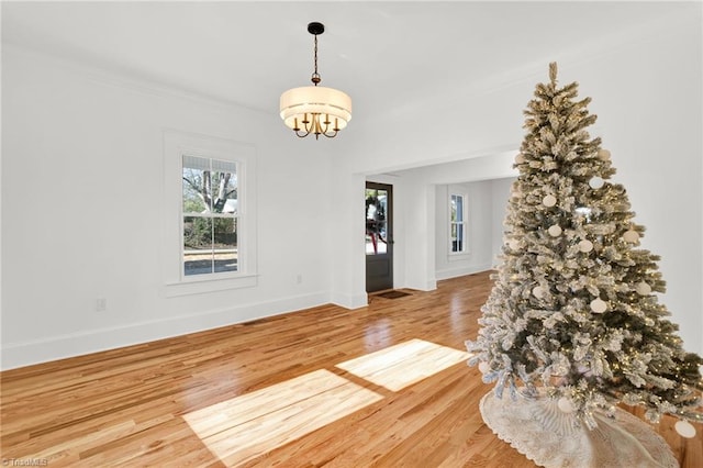 unfurnished room with wood-type flooring and an inviting chandelier