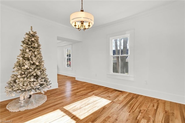 unfurnished dining area with a chandelier, hardwood / wood-style floors, and crown molding