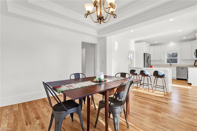 dining area featuring a tray ceiling, crown molding, a notable chandelier, and light wood-type flooring