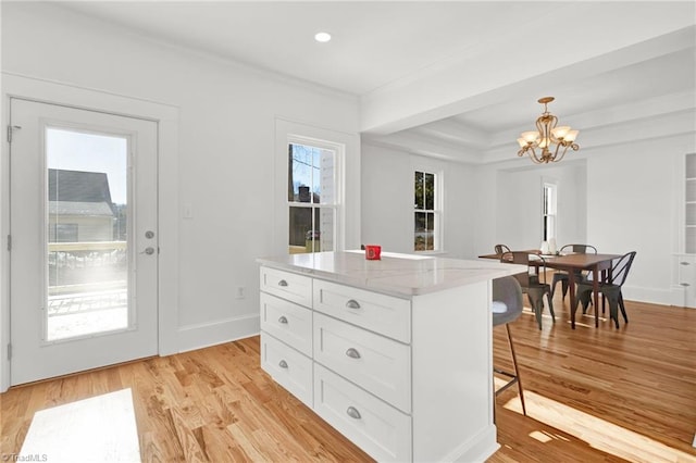 kitchen with a center island, hanging light fixtures, a notable chandelier, light hardwood / wood-style floors, and white cabinetry