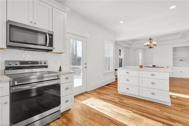 kitchen with appliances with stainless steel finishes, tasteful backsplash, a chandelier, light hardwood / wood-style floors, and white cabinetry