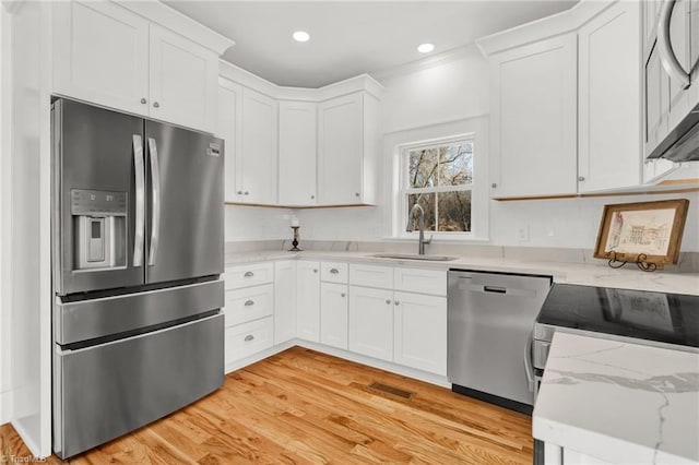 kitchen with light hardwood / wood-style floors, sink, white cabinetry, and stainless steel appliances