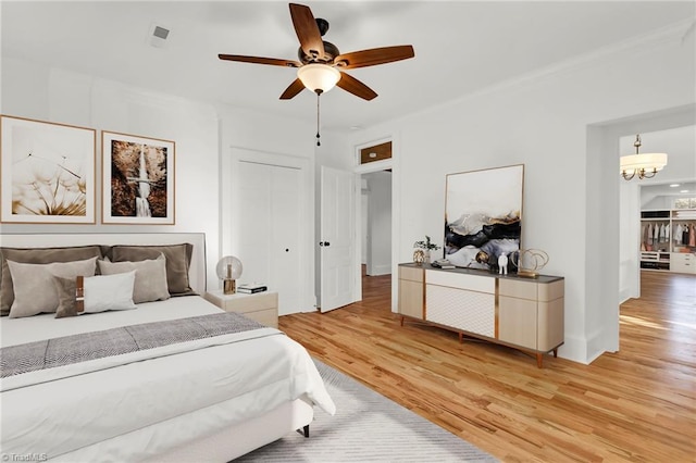 bedroom featuring ceiling fan with notable chandelier and light hardwood / wood-style flooring