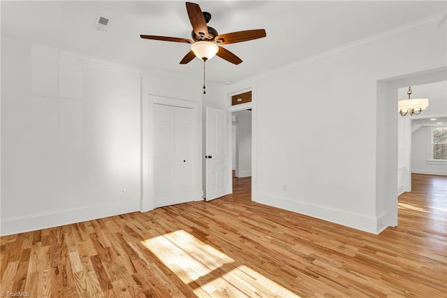 unfurnished room featuring ceiling fan with notable chandelier and light hardwood / wood-style floors