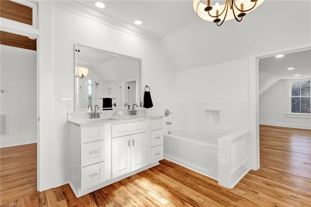 bathroom featuring vanity, vaulted ceiling, a bath, wood-type flooring, and an inviting chandelier