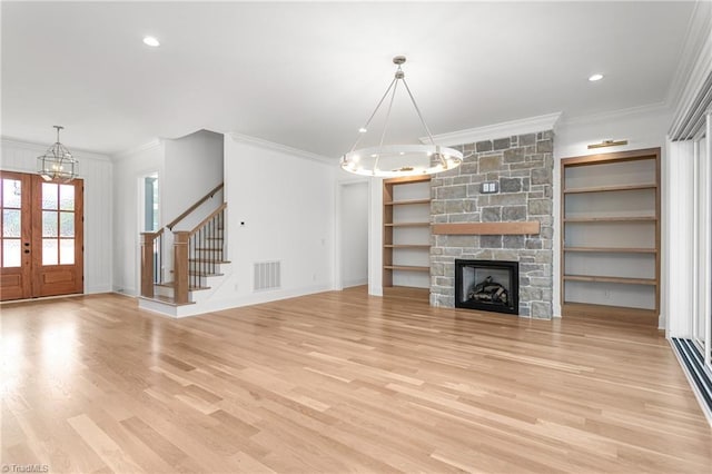 unfurnished living room featuring light wood finished floors, visible vents, a chandelier, stairs, and ornamental molding