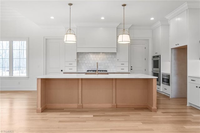 kitchen with light countertops, a large island, crown molding, double oven, and backsplash