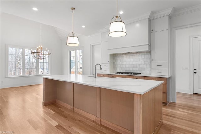 kitchen featuring premium range hood, light wood-style flooring, a spacious island, gas stovetop, and decorative backsplash