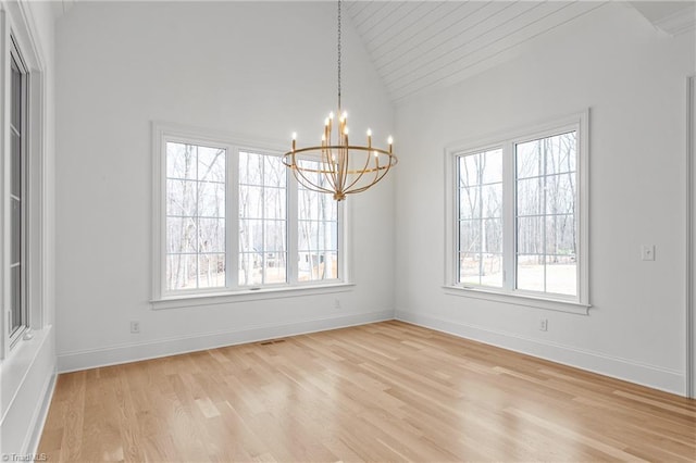 unfurnished dining area with vaulted ceiling, light wood-style flooring, baseboards, and a chandelier