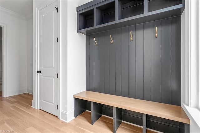 mudroom with crown molding, baseboards, and light wood finished floors
