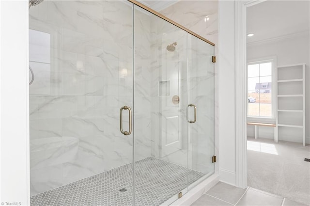 full bath with a marble finish shower, tile patterned floors, and ornamental molding