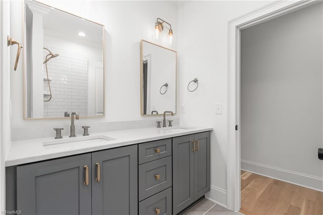 bathroom featuring double vanity, wood finished floors, baseboards, and a sink