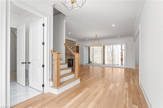 staircase with an inviting chandelier, wood finished floors, and ornamental molding