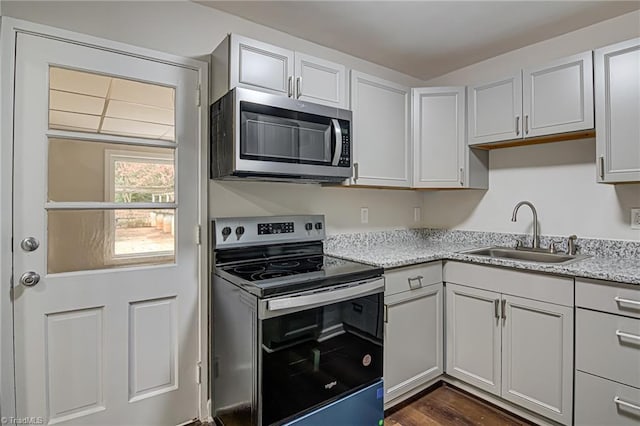 kitchen with light stone countertops, appliances with stainless steel finishes, white cabinetry, and sink