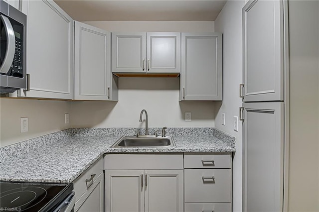 kitchen featuring light stone counters, white cabinetry, and sink