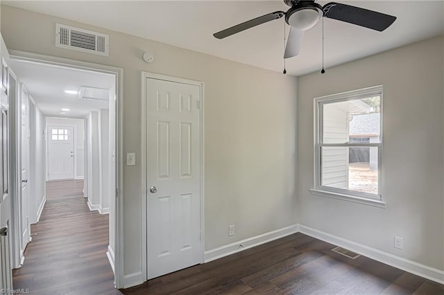 unfurnished bedroom with multiple windows, dark hardwood / wood-style flooring, and ceiling fan