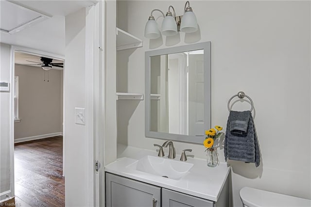 bathroom with hardwood / wood-style floors, vanity, ceiling fan, and toilet