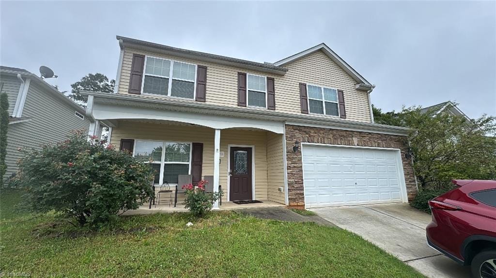 3858 Robbins Brook Dr, Winston-Salem, NC 27107 - view of front facade featuring covered porch, a garage, concrete driveway, a front yard, and stone siding