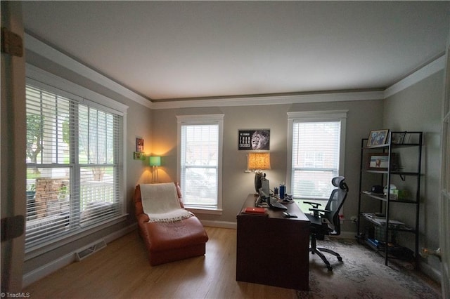 office with a healthy amount of sunlight, ornamental molding, and hardwood / wood-style flooring