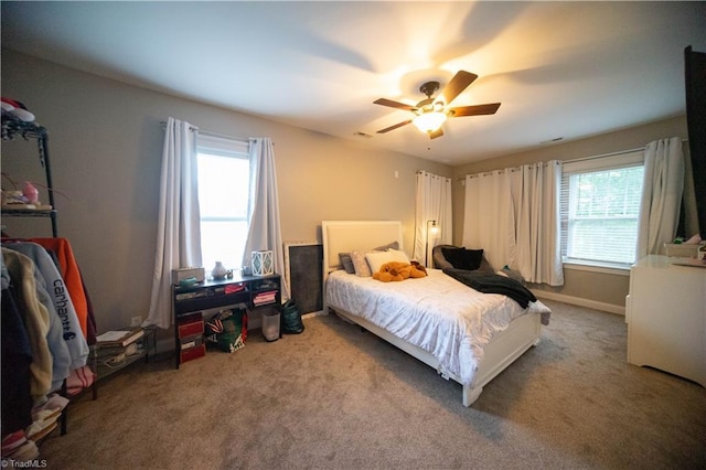 carpeted bedroom featuring multiple windows and ceiling fan