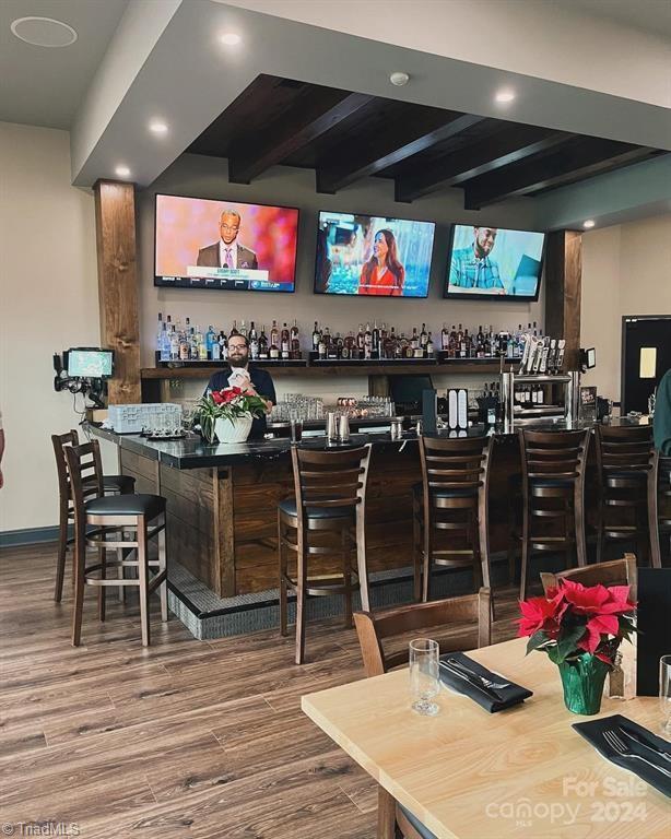 bar featuring beam ceiling and wood-type flooring